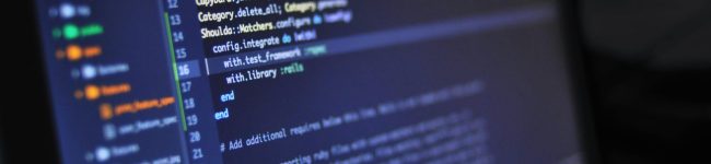 Close-up of a computer screen displaying programming code in a dark environment.